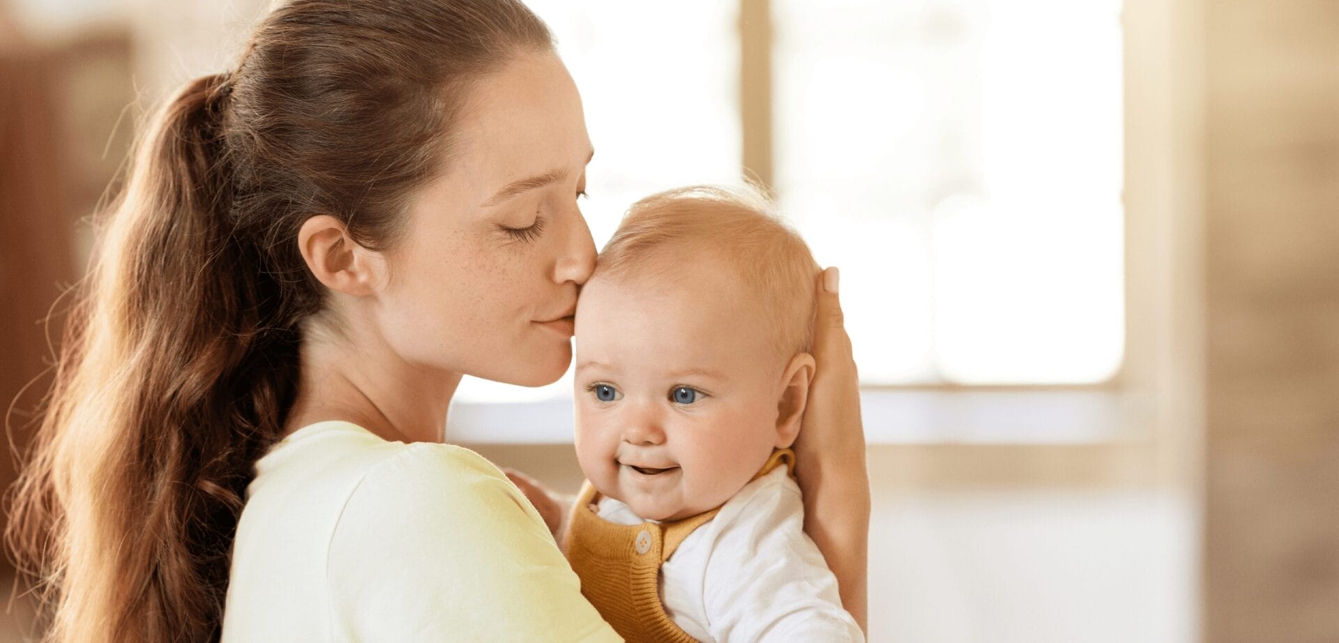 Zdjęcie kobiety całującej niemowlę w policzek.